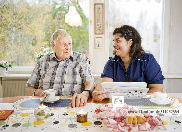Krankenschwester mit älterem Mann am Tisch  Schweden