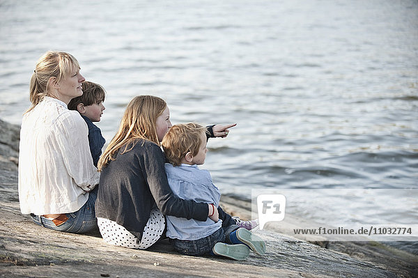 Mutter mit drei Kindern sitzt am Wasser  Nacka  Schweden