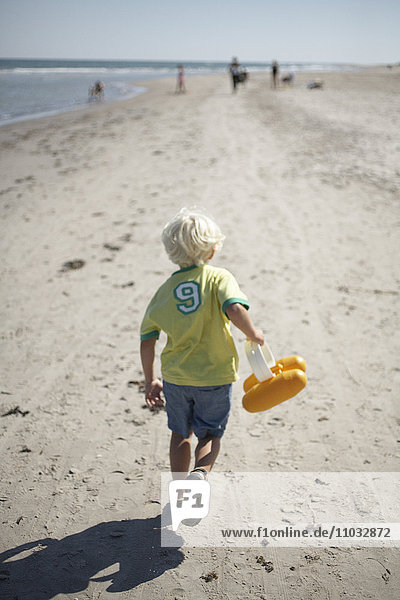 Ein Junge läuft am Strand.