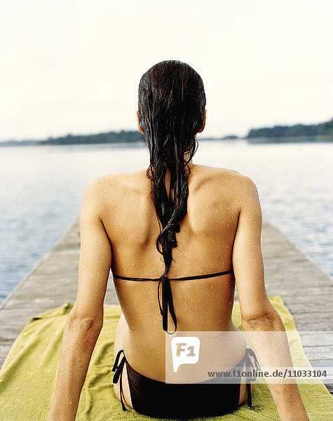 Eine Frau nimmt ein Sonnenbad auf einem Steg.