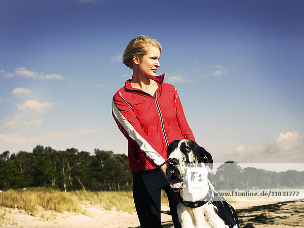 A woman and a dog on the beach.