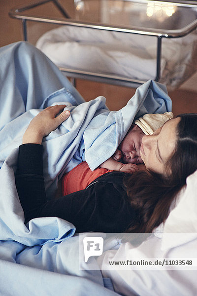Schlafende Mutter mit neugeborenem Baby im Krankenhausbett