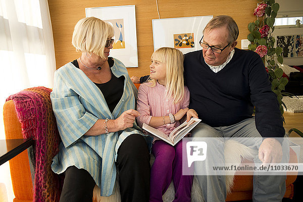 Grandparents reading book with granddaughter
