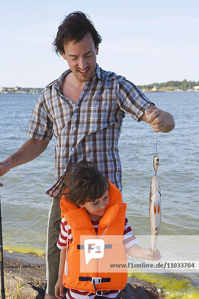 Vater und Sohn mit einem gefangenen Fisch.