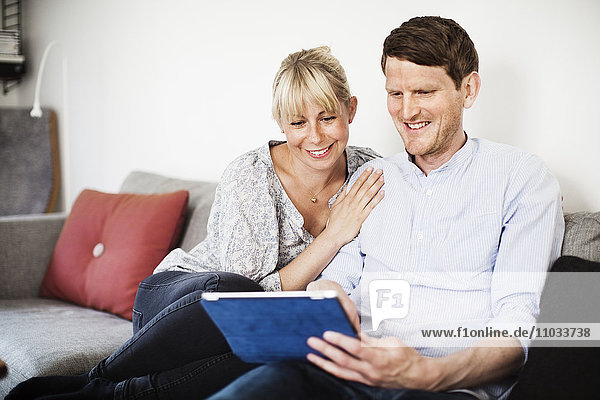 A couple sitting in a sofa with a tablet
