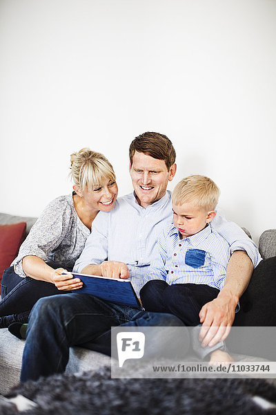 A family sitting in a sofa with a tablet