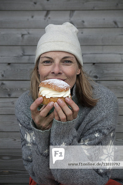 Porträt einer Frau in warmer Kleidung  die Kuchen isst