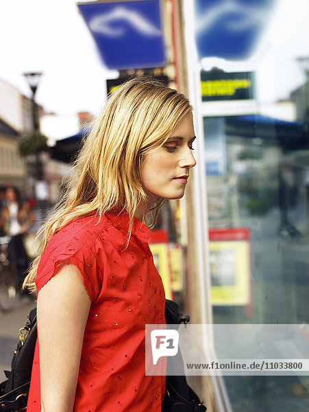 Eine junge Frau  die durch ein Schaufenster schaut.
