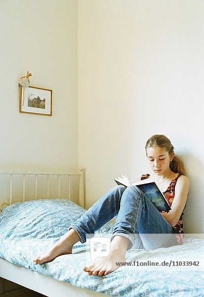 Ein junges Mädchen liest in ihrem Bett.