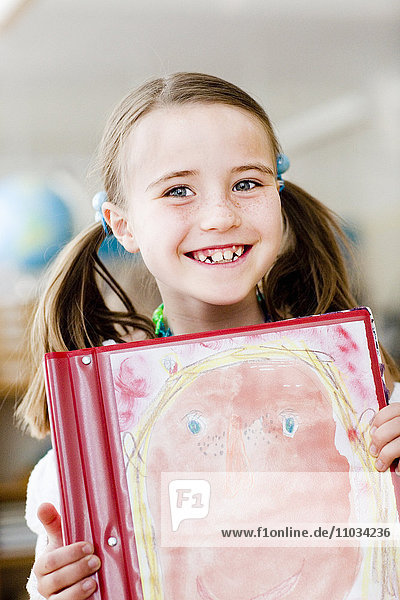 Porträt eines lächelnden Mädchens  das ein Gemälde in einem Klassenzimmer zeigt  Schweden.