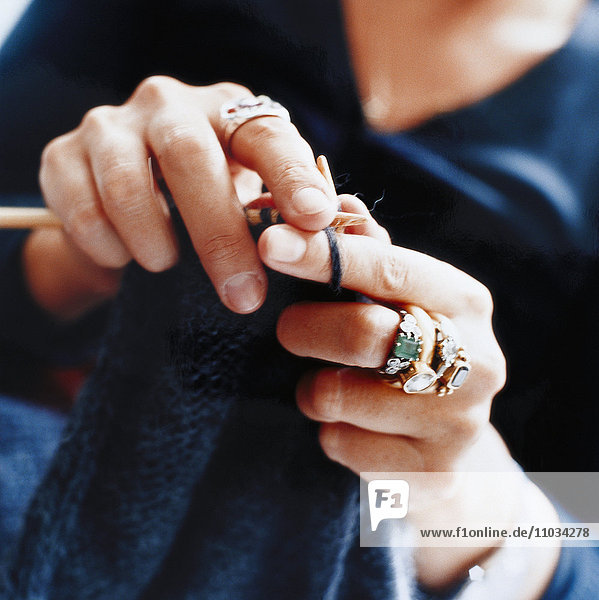 Closeup of woman's hand knitting a sweater.
