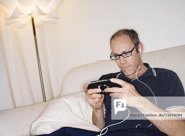 Ein Mann spielt ein Fernsehspiel auf einer PSP  Schweden.