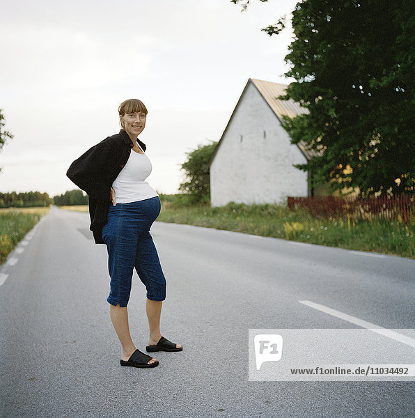 Schwangere Frau  die auf einer Straße steht.