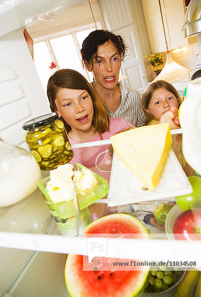 Mutter und Mädchen nehmen Essen aus dem Kühlschrank.