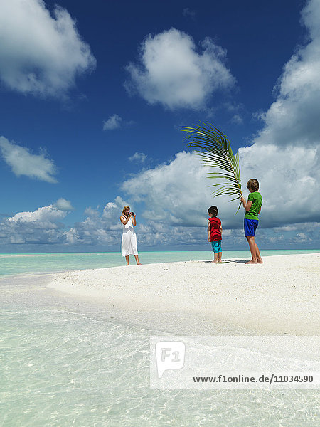 Jungen spielen am Sandstrand  während die Mutter ein Foto macht
