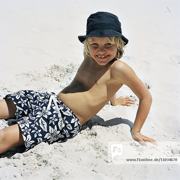 Portrait of a smiling boy lying on the beach  Sweden.