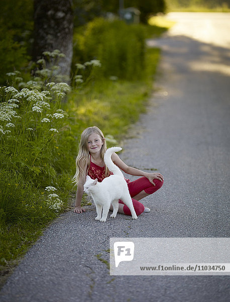 Lächelndes Mädchen auf der Straße mit weißer Katze