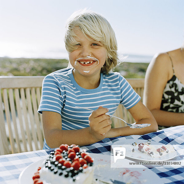Porträt eines lächelnden Jungen  der einen Kuchen isst  Schweden.