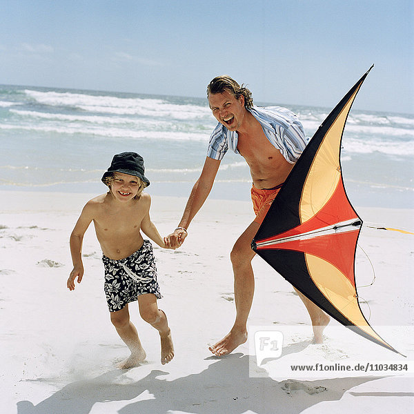 Father and a son playing with a kite on the beach  Sweden.