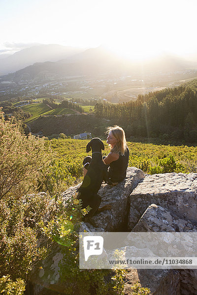 Frau mit Hund bei Sonnenuntergang