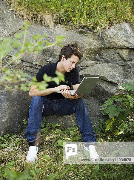 A teenage boy with a computer outside  Sweden.