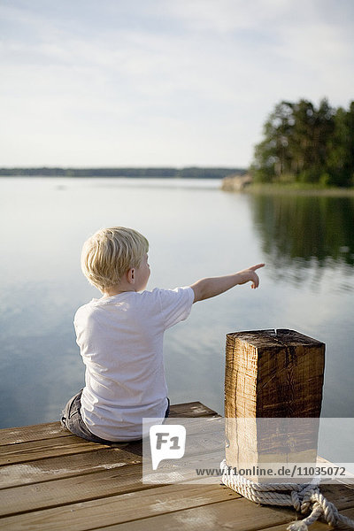 Ein Junge sitzt auf einem Bootssteg  Schweden.