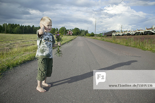 Boy holding wildflowers bouquet on road