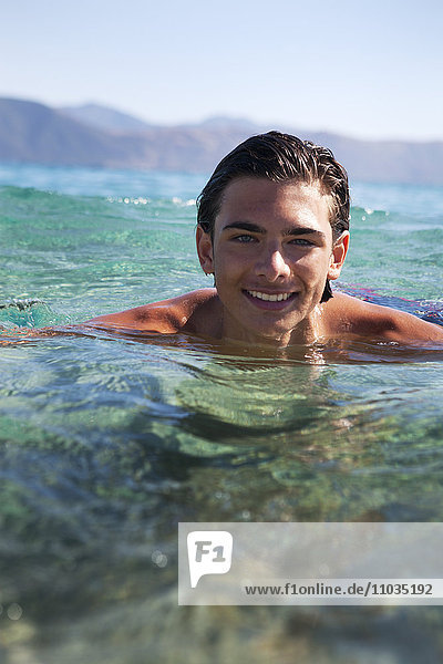 Smiling teenage boy bathing in sea