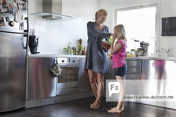 Lächelnde reife Frau in der Küche mit Tochter