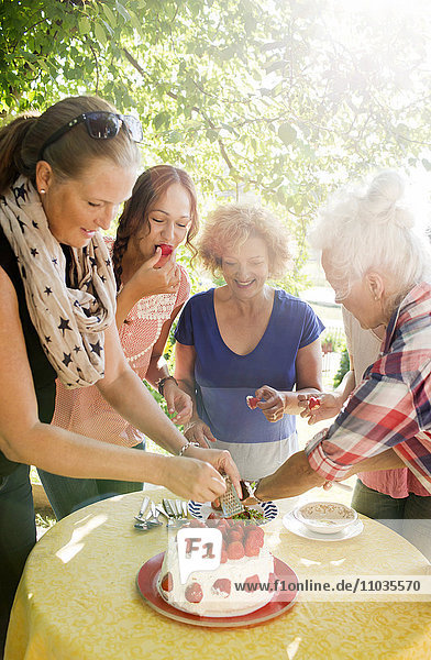 Vier Frauen bereiten Erdbeerkuchen im Garten vor