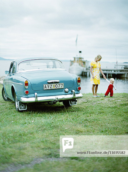 Mutter und Kind neben einem alten Auto  Schweden.