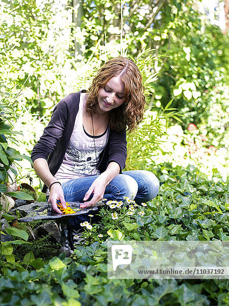 Teenage girl by a birdbath in a garden  Sweden.