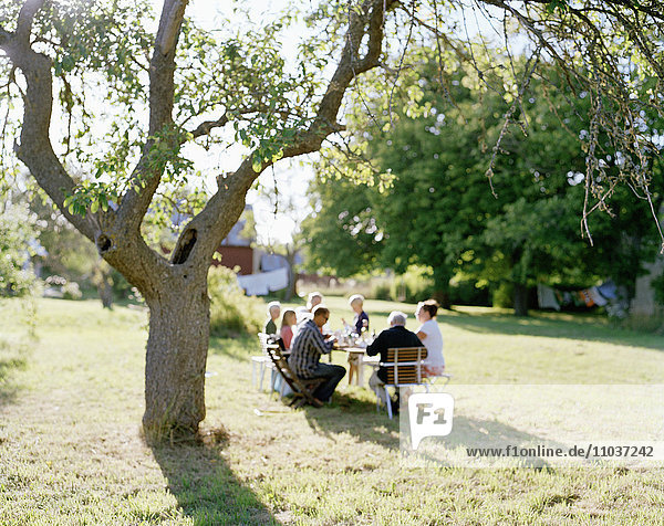 Multi-generation family having dinner in the garden  Sweden.
