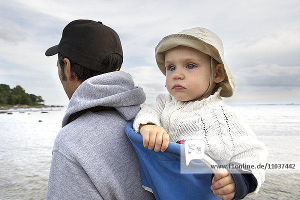 Kleinkind in einer Babytrage auf dem Rücken seines Vaters  Schweden.