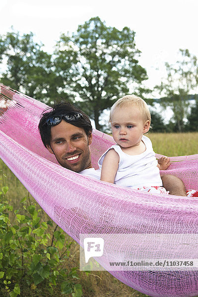 Vater und Kleinkind in einer Hängematte  Schweden.