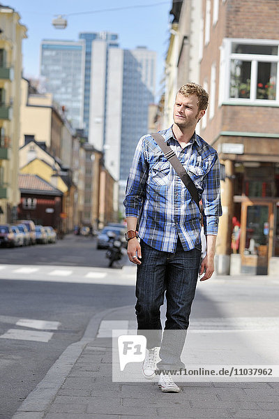 Junger Mann geht auf einer Straße  Schweden.