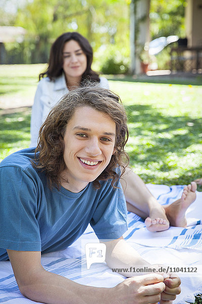 Man relaxing on picnic blanket with friend