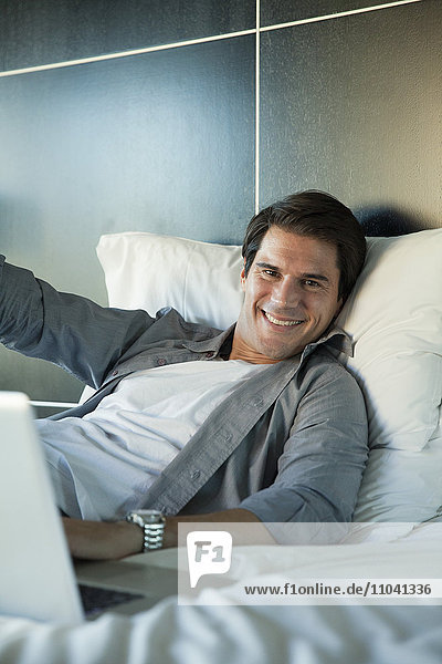 Mann auf dem Bett liegend  fröhlich lächelnd  Portrait
