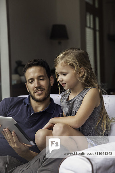 Father and daughter using digital tablet together