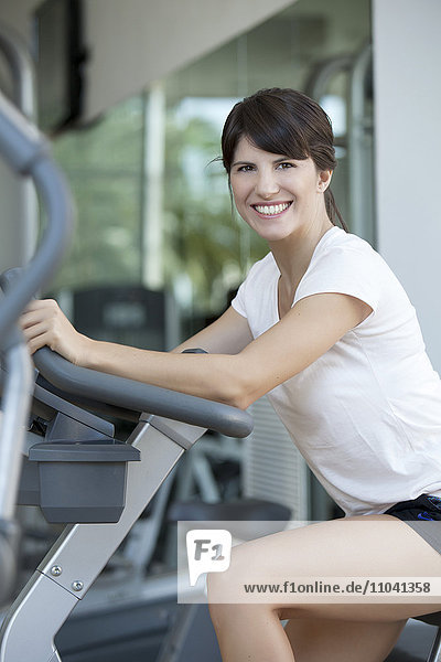 Frau  die im Fitnessstudio trainiert  lächelt fröhlich.