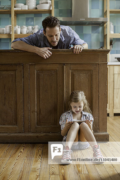 Father looking on as daughter plays video game