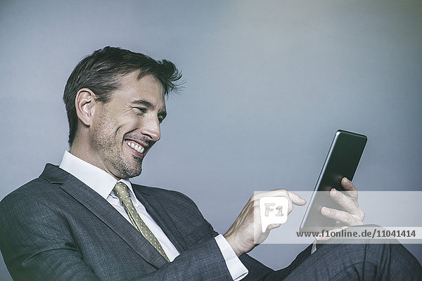 Der Mann lacht  während er ein digitales Tablett benutzt.