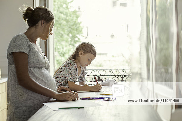 Mother watching daughter coloring
