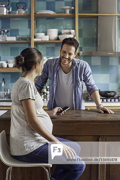 Schwangere Frau im Gespräch mit Mann in der Küche