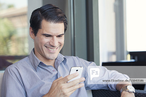 Man using smartphone and smiling cheerfully