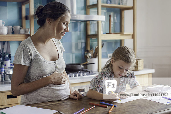 Pregnant mother watching daughter draw