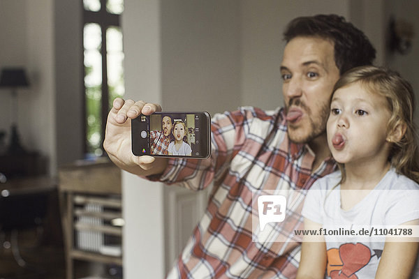 Father and daughter making funny faces selfie