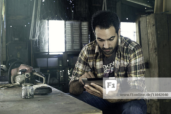 Mann benutzt digitales Tablett  um während der Arbeitspause auf das Internet zuzugreifen.