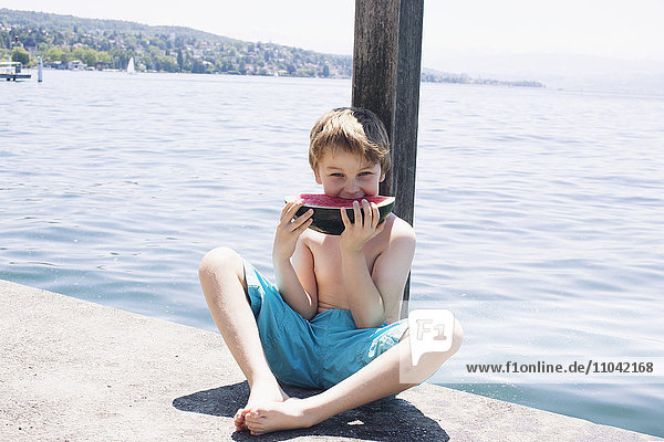Junge isst Wassermelone am Dock