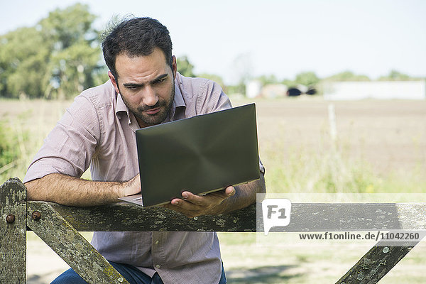 Landwirt mit Laptop auf dem Feld